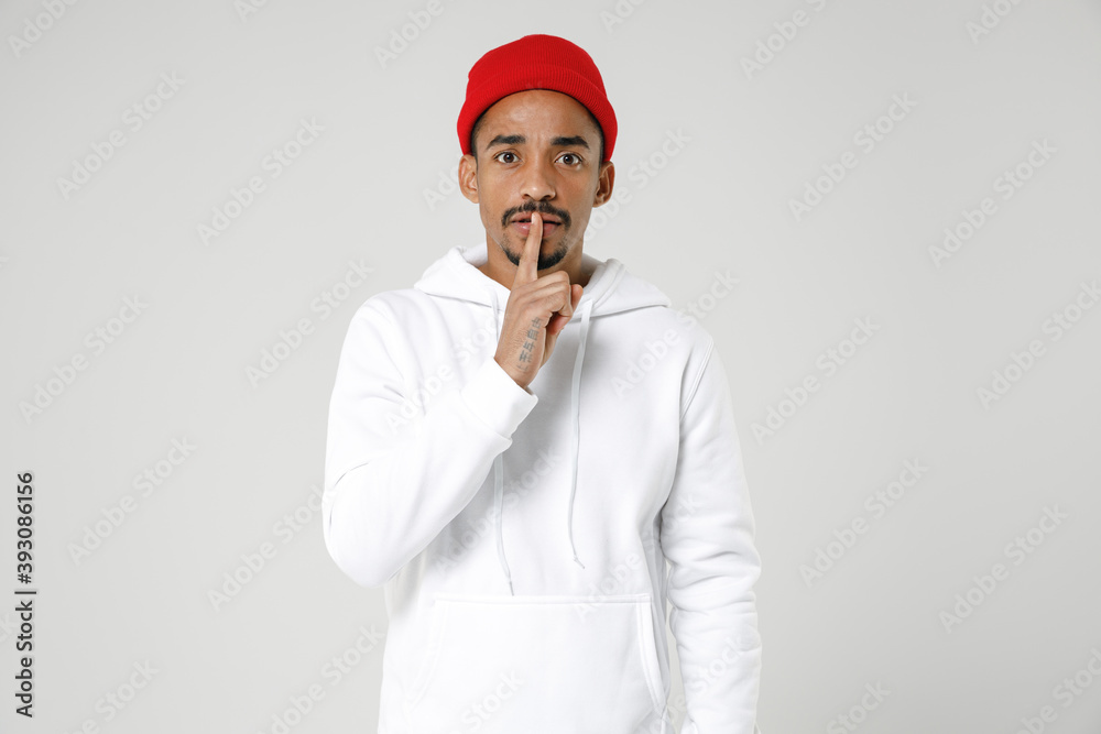 Secret young african american man 20s years old wearing basic casual streetwear hoodie saying hush be quiet with finger on lips shhh gesture isolated on white colour wall background studio portrait. Secret young african american man 20s years old wearing basic casual streetwear hoodie saying hush be quiet with finger on lips shhh gesture isolated on white colour wall background studio portrait.