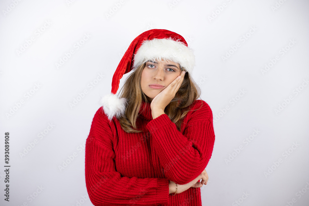 Young pretty blonde woman wearing a red casual sweater and a christmas hat over white background thinking looking tired and bored with crossed arms Young pretty blonde woman wearing a red casual sweater and a christmas hat over white background thinking looking tired and bored with crossed arms