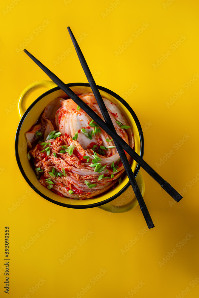 Kimchi cabbage in a bowl with chopsticks on a colored background, top view, Korean cuisine. Trend food photography Kimchi cabbage in a bowl with chopsticks on a colored background, top view, Korean cuisine. Trend food photography