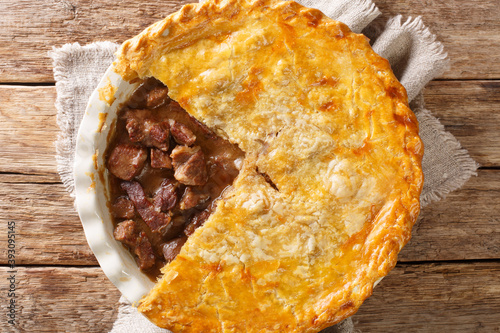 steak pie is a traditional meat pie served in Britain it is made from stewing steak and beef gravy, enclosed in a pastry closeup in the dish on the table. horizontal top view from above