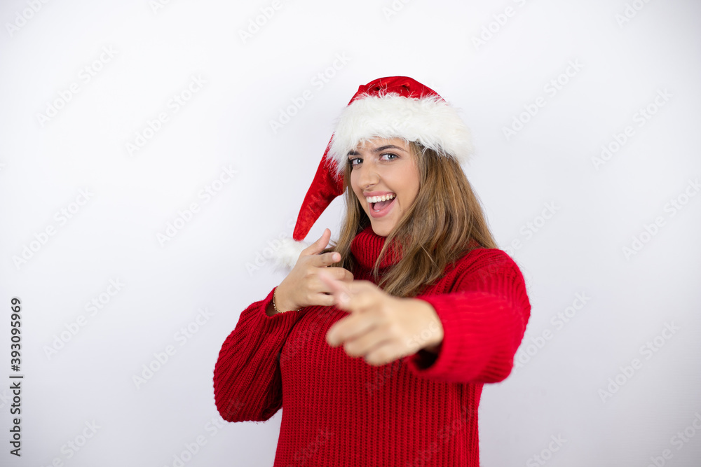 Young pretty blonde woman wearing a red casual sweater and a christmas hat over white background pointing to you and the camera with fingers, smiling positive and cheerful Young pretty blonde woman wearing a red casual sweater and a christmas hat over white background pointing to you and the camera with fingers, smiling positive and cheerful