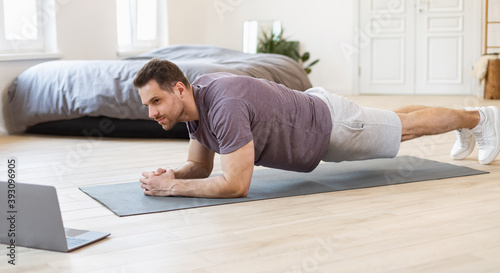 Sporty Guy Training At Computer Online Doing Plank Indoor, Panorama