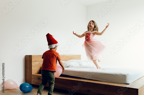 playful toddlers having a fun time dancing and playing with balloons on parents bed
