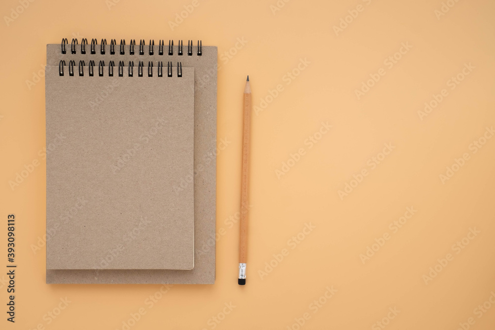 Top view above of Two school book brown closed spiral blank paper cover notebook with pencil isolated on blue background for design a mockup. Education and business concept. flat lay Top view above of Two school book brown closed spiral blank paper cover notebook with pencil isolated on blue background for design a mockup. Education and business concept. flat lay