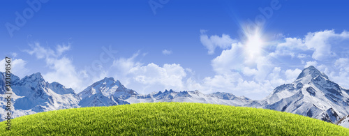 Sunny natural background with grassy hill, snowy high mountain peaks and clear blue sky - great copy-space for posters, cards or banners (all composition elements shot by myself)