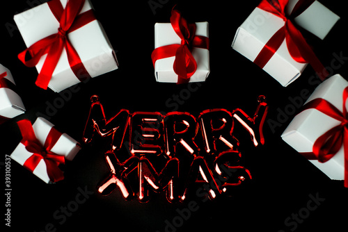 White gifts with red ribbons with inscription: Merry Christmas.Set of gift box flat lay, copy space. Christmas gift boxes on black background. Merry Christmas and Happy Holidays greeting card, banner