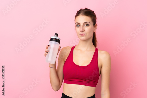 Young sport woman over isolated pink background with sports water bottle