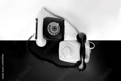two vintage telephone sets with dial in retro style on a black, white background, concept of old communication technologies, harmony of relationships, masculine and feminine principles, yin yang photo