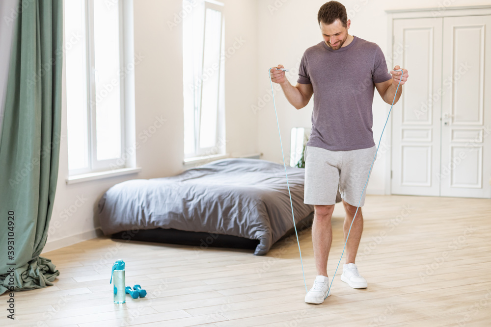 Man Exercising With Jumping Rope At Home, Wearing Casual Clothes Man Exercising With Jumping Rope At Home, Wearing Casual Clothes