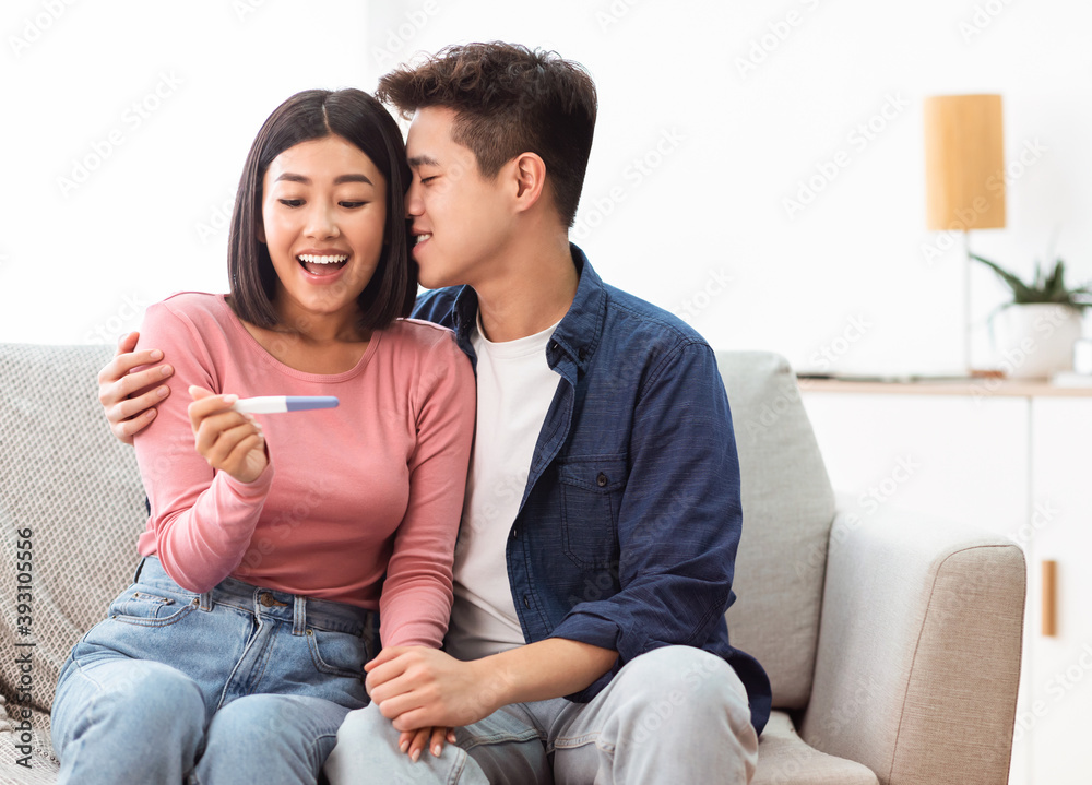 Husband And Wife Celebrating Getting Positive Result Of Pregnancy Test