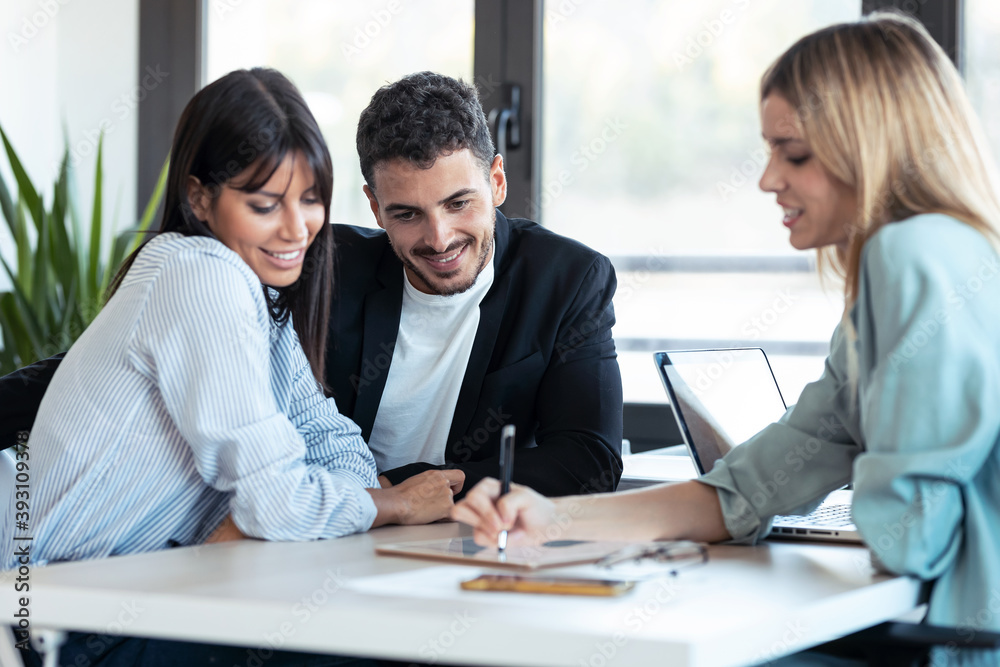 Φωτογραφία Beautiful real-estate agent showing house plans on electronic tablet while talking to the couple about buying the house in the office