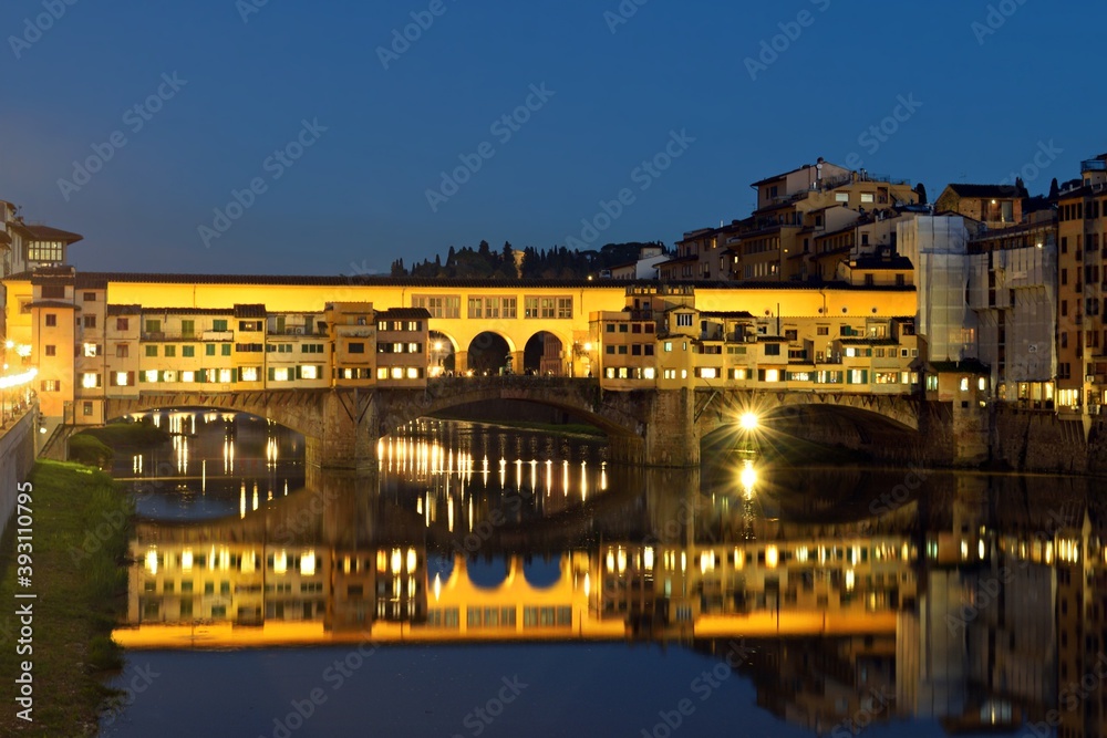 night landscape of the beautiful Ponte Vecchio in the city of Florence in Italy reflected in the water of the Arno river