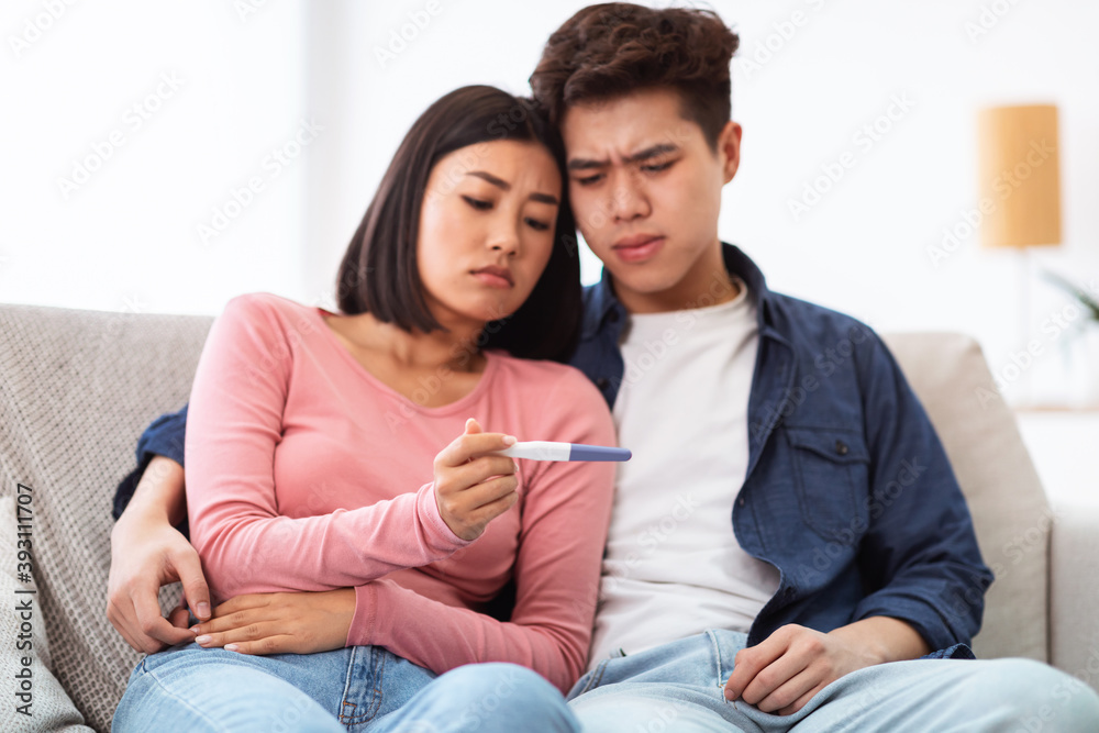 Frustrated Japanese Couple Holding Negative Pregnancy Test At Home Frustrated Japanese Couple Holding Negative Pregnancy Test At Home