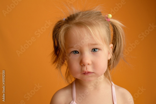 A girl at the age of one and a half years. Close-up. The girl's snot is flowing. The girl is sick. Place for text. Studio photo session. Photographed with a yellow background.