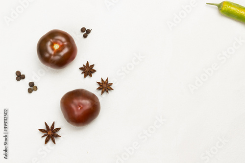 Two tomatoes and spices, star anise, peppercorns.