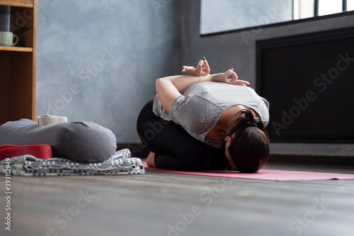Full length of a young woman sitting in child pose on a yoga mat at home. photo