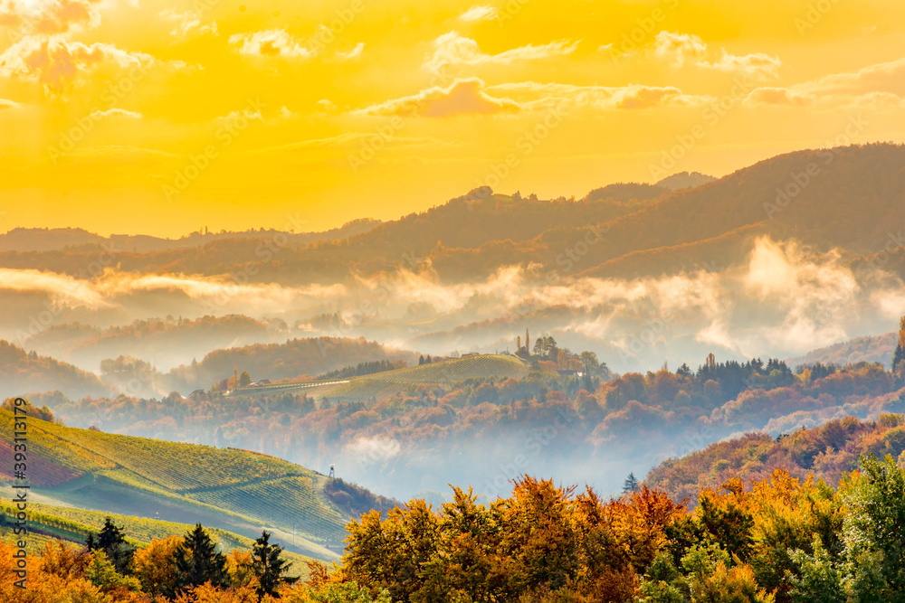 Fototapeta premium Autumn landscape with South Styria vineyards,known as Austrian Tuscany,a charming region on the border between Austria and Slovenia with rolling hills,picturesque villages and wine taverns,at sunrise