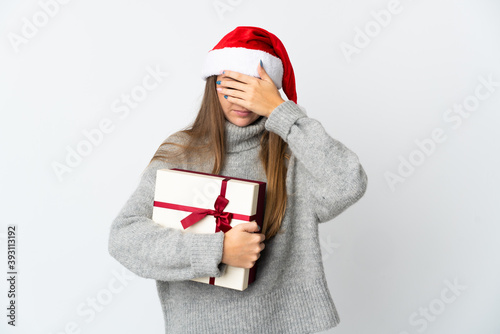 Lithianian woman with christmas hat holding presents isolated on white background covering eyes by hands. Do not want to see something