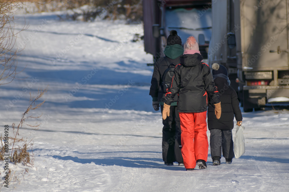 Three children walk along a winter village road