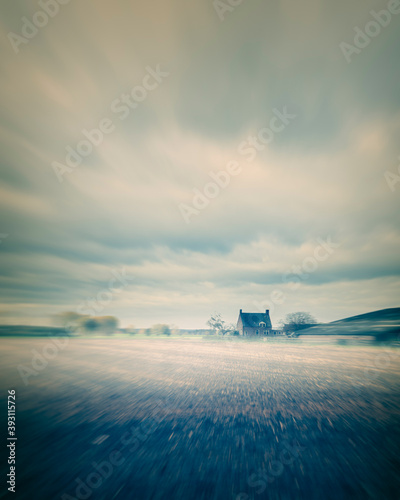 Misty countryside with old house and cow shed.