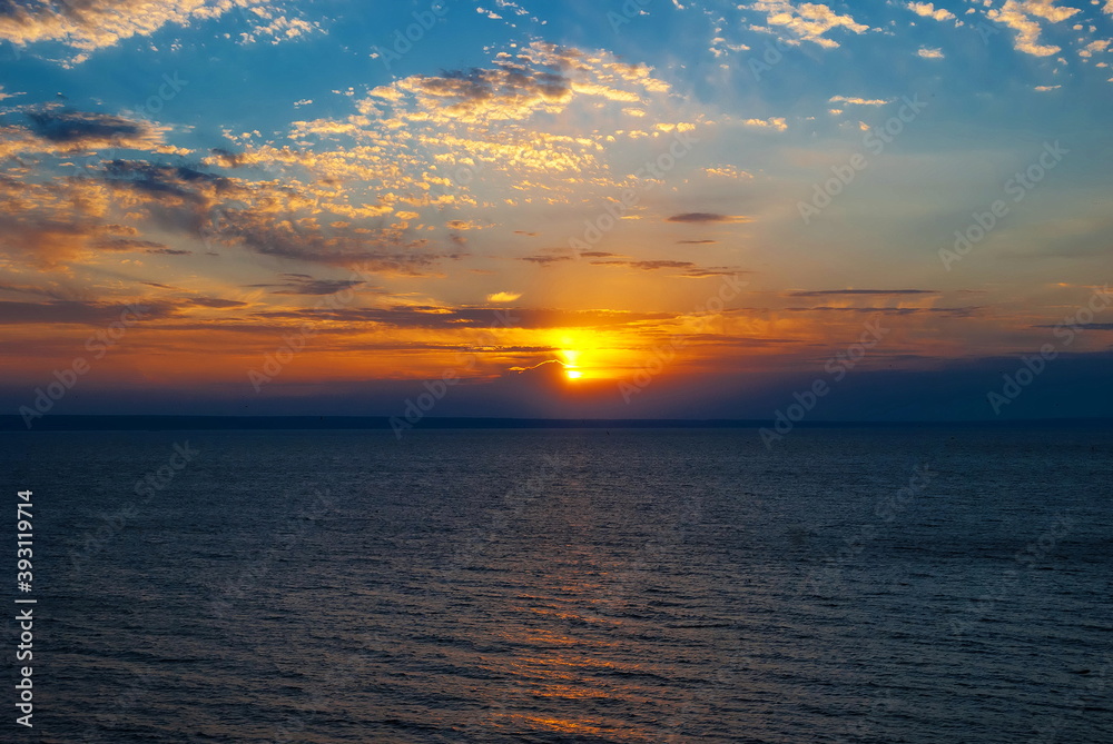 Bright sunset sky with beautiful clouds above water