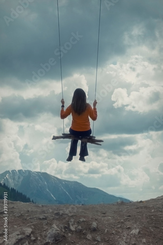 The girl swings on a swing over the mountains, a feeling of flight and freedom.