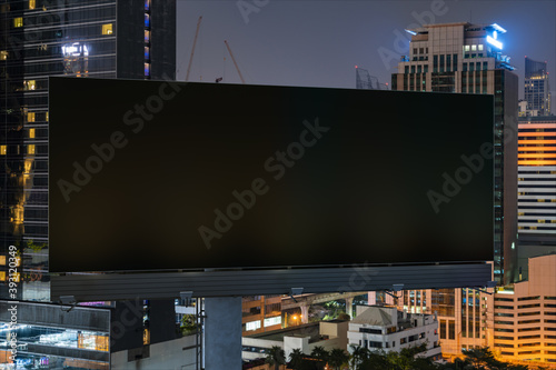 Blank black road billboard with Bangkok cityscape background at night time. Street advertising poster, mock up, 3D rendering. Front view. The concept of marketing communication to sell idea.