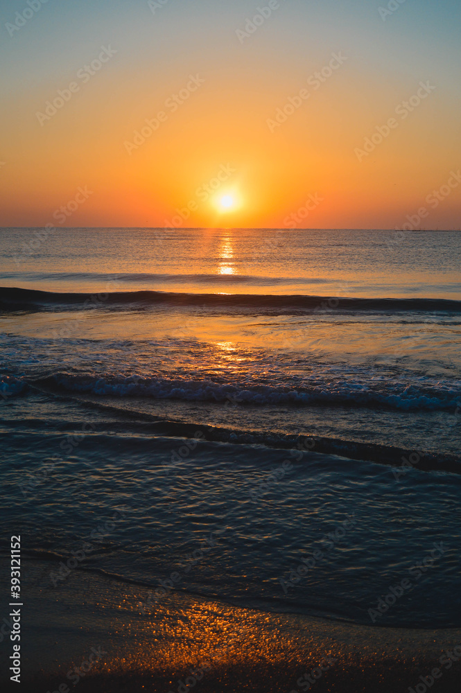 Beautiful summer sunset at the beach, waves and sand