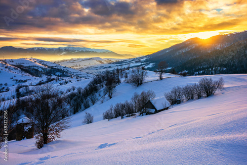 winter landscape in mountains at sunrise. beautiful rural area of carpathian mountains with snow covered hills. glowing clouds on the sky. frosty weather © Pellinni
