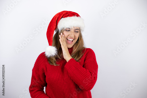 Young pretty blonde woman wearing a red casual sweater and a christmas hat over white background hand on mouth telling secret rumor  whispering malicious talk conversation