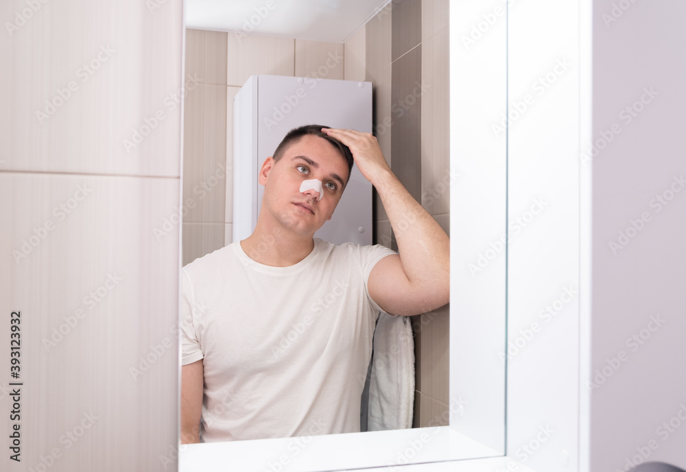 man puts on and removes a strip for the nose from black dots. Coal cleaning strips from blackheads and comedones. The concept of personal care. man puts on and removes a strip for the nose from black dots. Coal cleaning strips from blackheads and comedones. The concept of personal care.