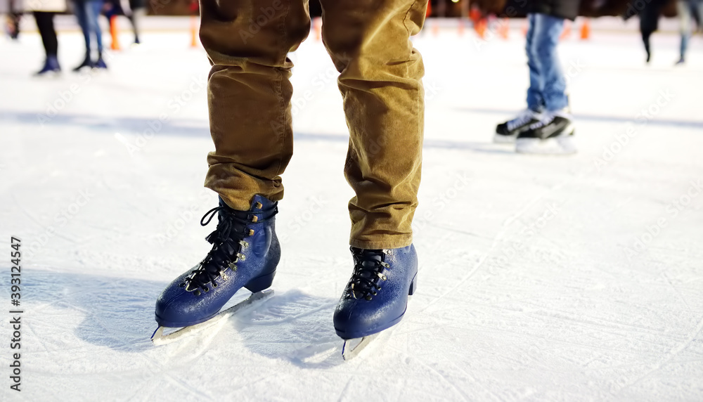 Man skating on rink Central Park on Christmas Eve. Legs of man standing on ice rink in skates close-up. Person learns to skate. Sports training for adult. Local having fun in New York in winter Man skating on rink Central Park on Christmas Eve. Legs of man standing on ice rink in skates close-up. Person learns to skate. Sports training for adult. Local having fun in New York in winter