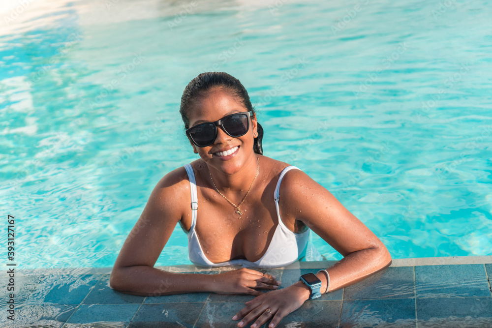 Beautiful African-American woman in white swimsuit at the pool