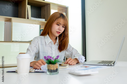 Asian Young Business women stress their job by scrunching up disapproved papers and throwing them in the office, a stress-to-work concept.