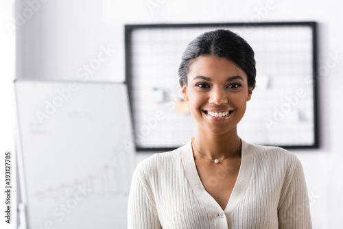 Smiling african american woman looking away while standing in office on blurred background Free Download Smiling african american woman looking away while standing in office on blurred background - GFXLoad