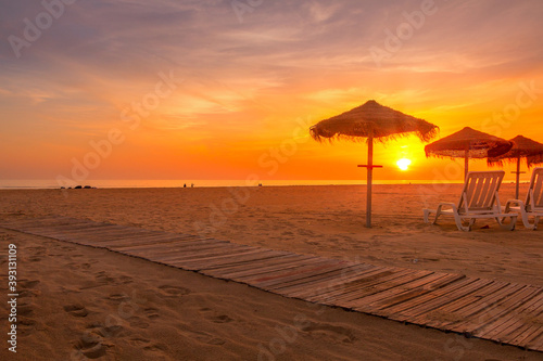 Autumn sunset at the beach with straw beach hats and sun loungers © WildGlass Photograph