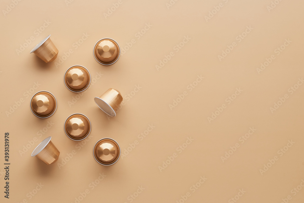 Caffeine, hot drinks and objects concept - close up of golden capsules or pods for coffee mashine on beige background. Top view with space for text. Flat lay.. Caffeine, hot drinks and objects concept - close up of golden capsules or pods for coffee mashine on beige background. Top view with space for text. Flat lay..