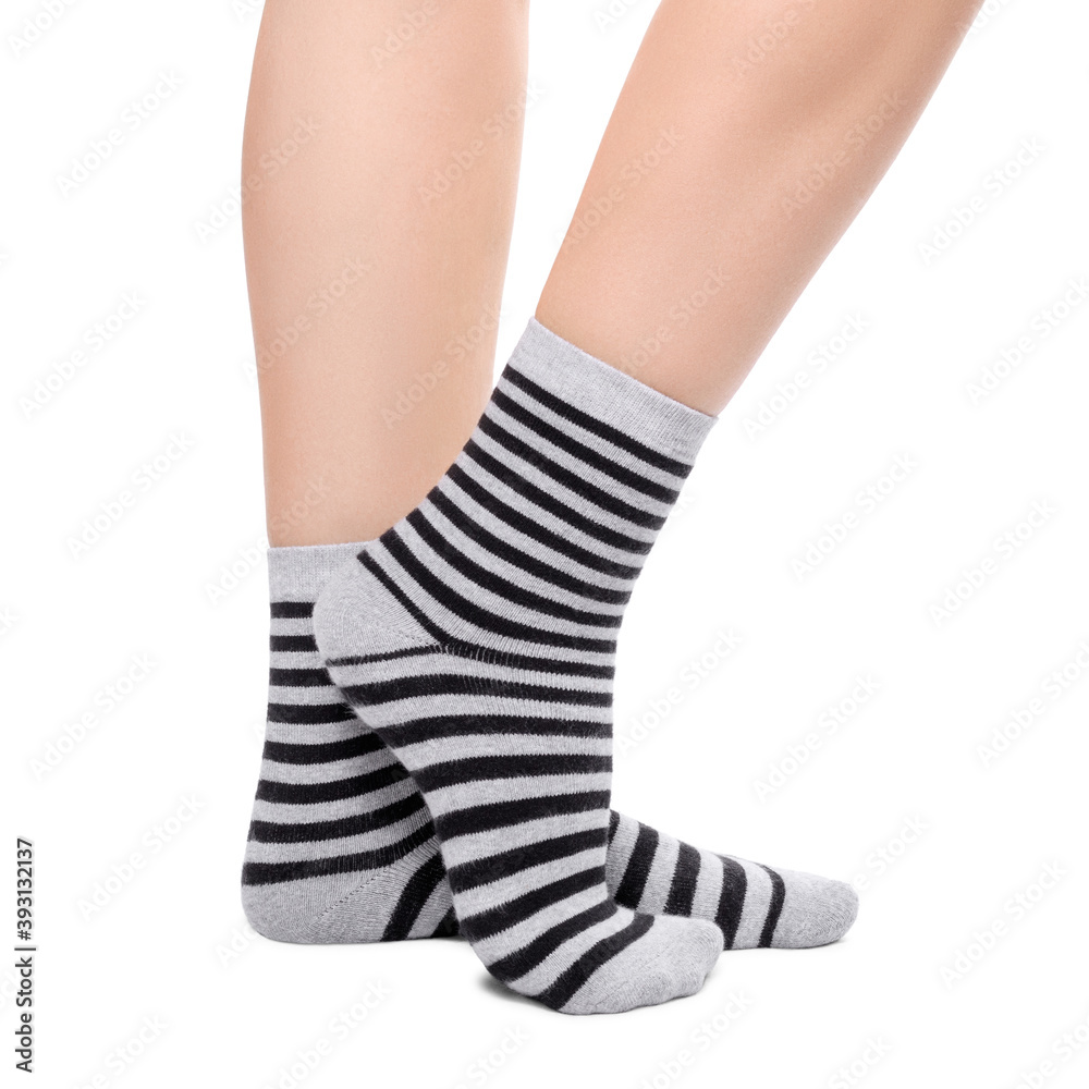 Female legs in warm striped black and grey socks isolated on white background.