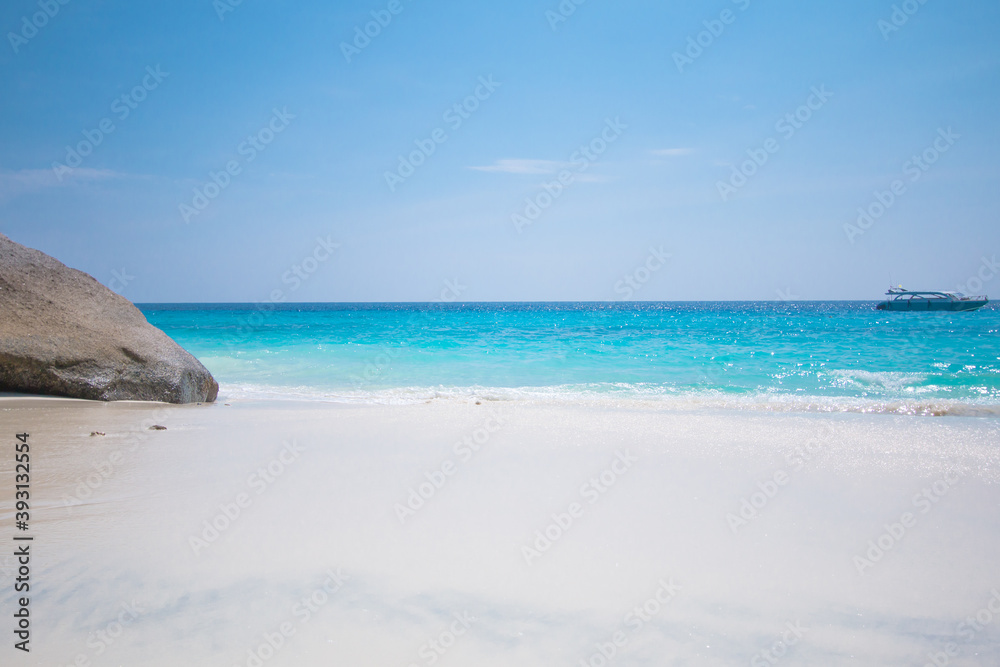 Beautiful beach, rock and boat with soft wave of blue ocean on sandy natural abstract texture background, copy space.
