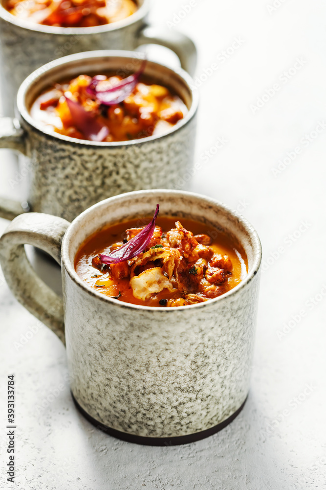 Pumpkin soup with chickpeas and crispy bacon is served in mugs. Pumpkin soup with chickpeas and crispy bacon is served in mugs.