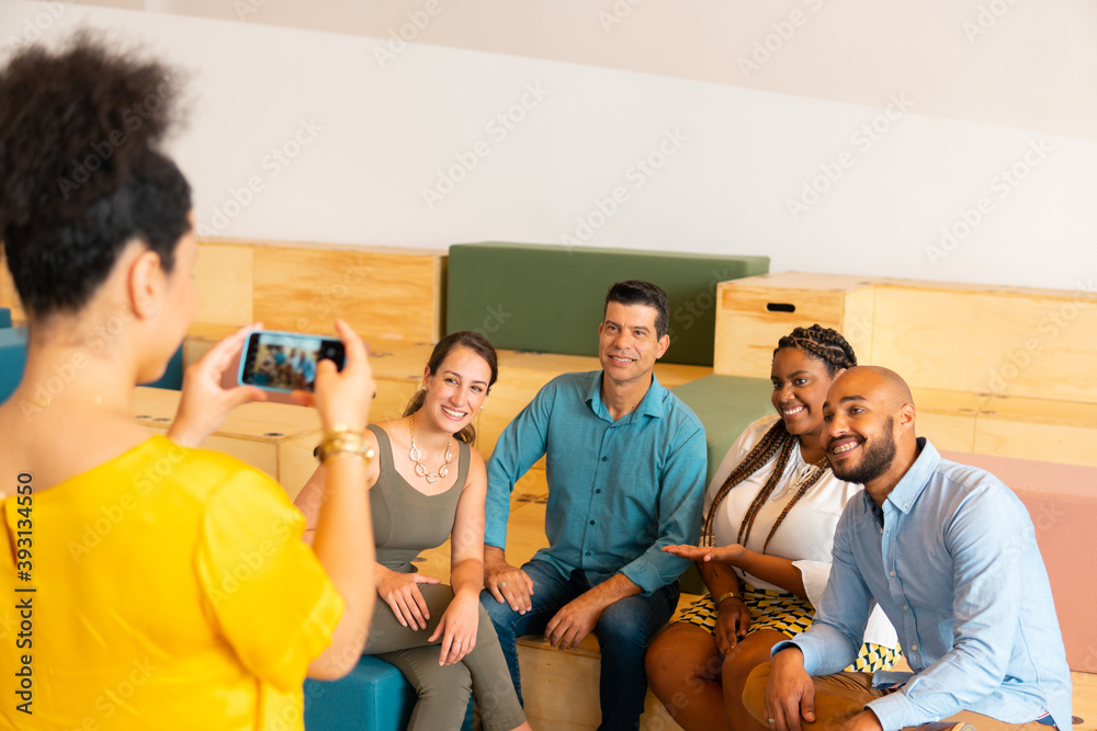 Happy team of business people taking a photograph in coworking open space. Partnership, teamwork, collaboration concept..