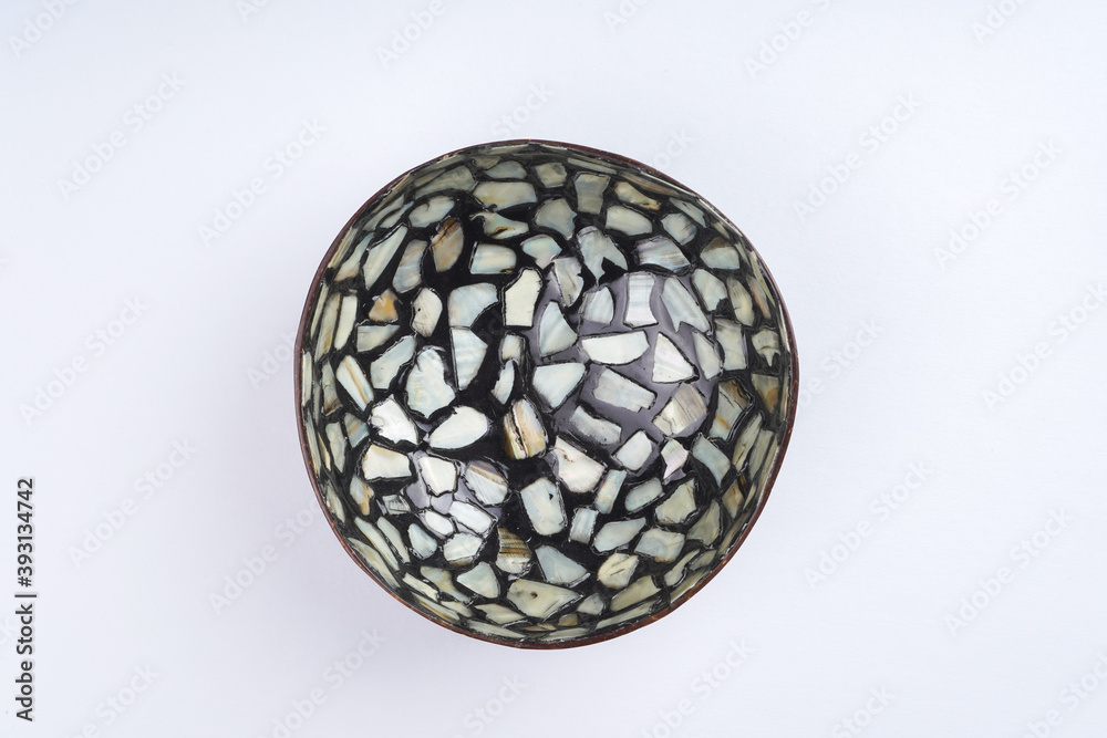 Black coconut shell bowl with pearl seashell pieces. Culinary, dishes concept. Top view, flat lay, copy space