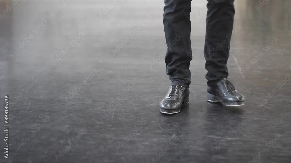 Single male tap dancer wearing black trousers and leather shoes dancing simple irish dance. Single male tap dancer wearing black trousers and leather shoes dancing simple irish dance.
