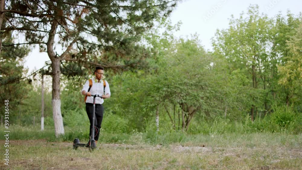 Attractive Afro American man office worker walking down the park with his electric scooter take a stop he is a bit tired Attractive Afro American man office worker walking down the park with his electric scooter take a stop he is a bit tired