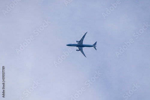 A portrait of a civilian airplane high up in the sky flying by. The belly of the airliner is visible.