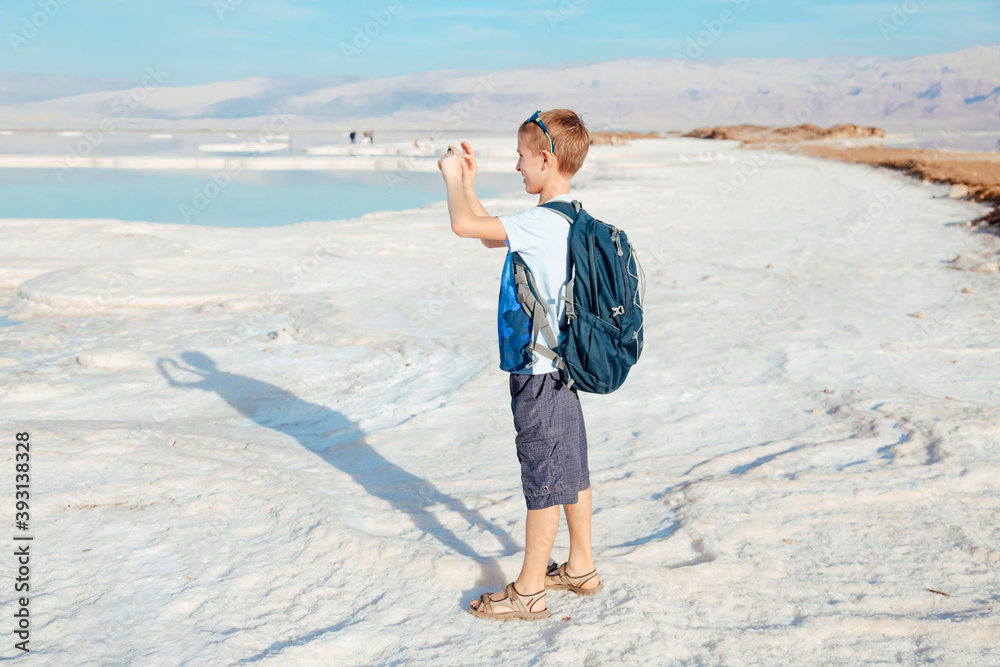 Blond boy enjoying bright day on Dead sea beautiful salt shore. Israel. Ein Bokek
