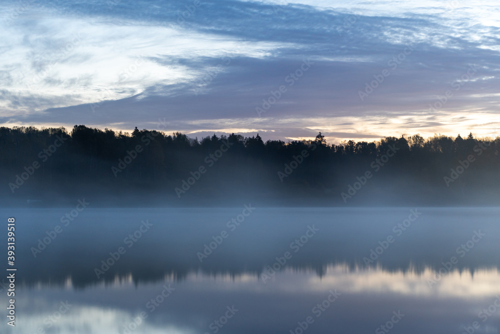 Lake at dawn in fog, windless, quiet morning, Trees on the opposite bank.