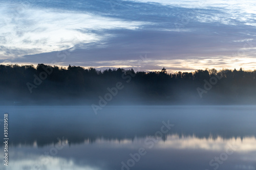 Lake at dawn in fog, windless, quiet morning, Trees on the opposite bank.