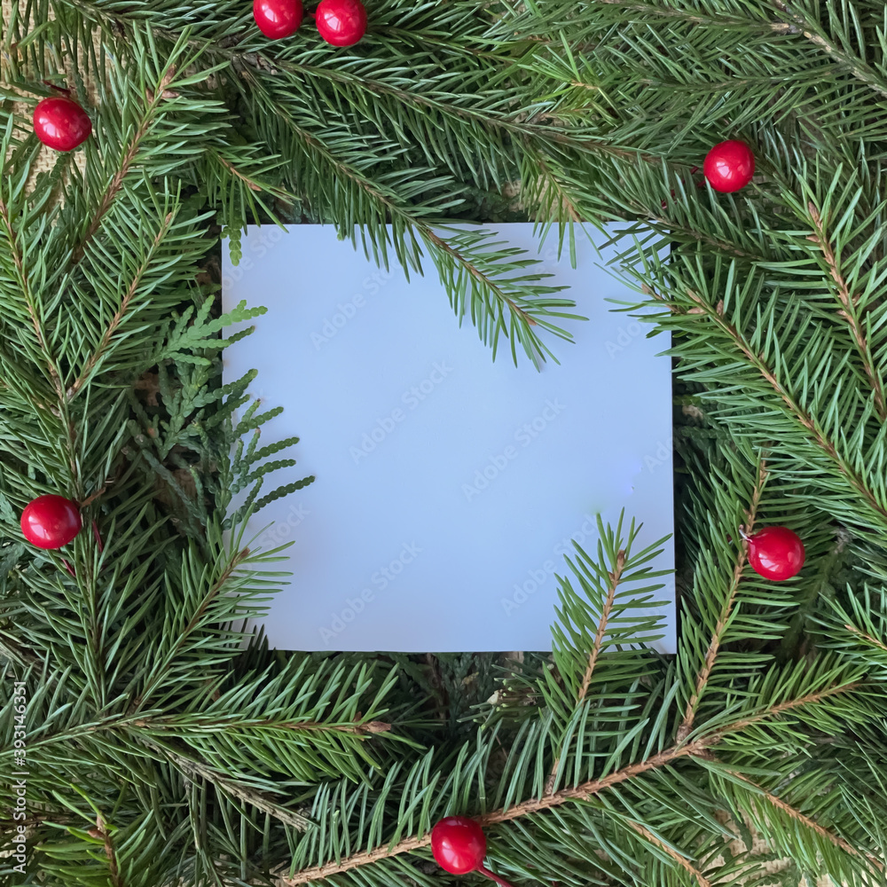 Christmas or New Year background. Decorative frame made of fir branches and red decor. A sheet of paper with copy space for your text. Flat lay, top view. New Year and Christmas concept. Christmas or New Year background. Decorative frame made of fir branches and red decor. A sheet of paper with copy space for your text. Flat lay, top view. New Year and Christmas concept.
