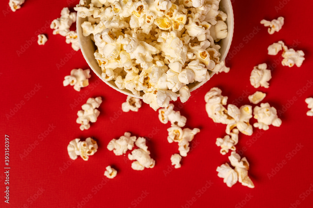 A bowl of popcorn on a red background, photo taken from above. A bowl of popcorn on a red background, photo taken from above.